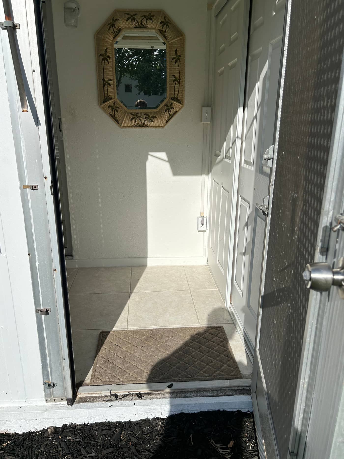 The same doorway clear, with the tiled entry, the mirror on the wall and the hallway beyond all visible