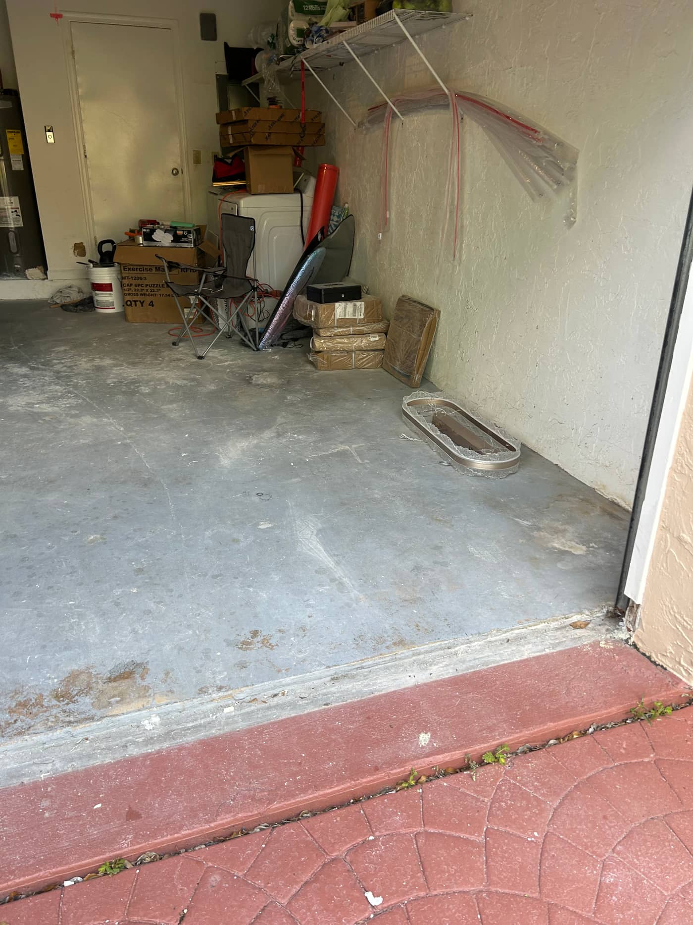 The same garage doorway with the pile gone, bare concrete floor visible to the back wall and only a folding chair and a few boxes left standing