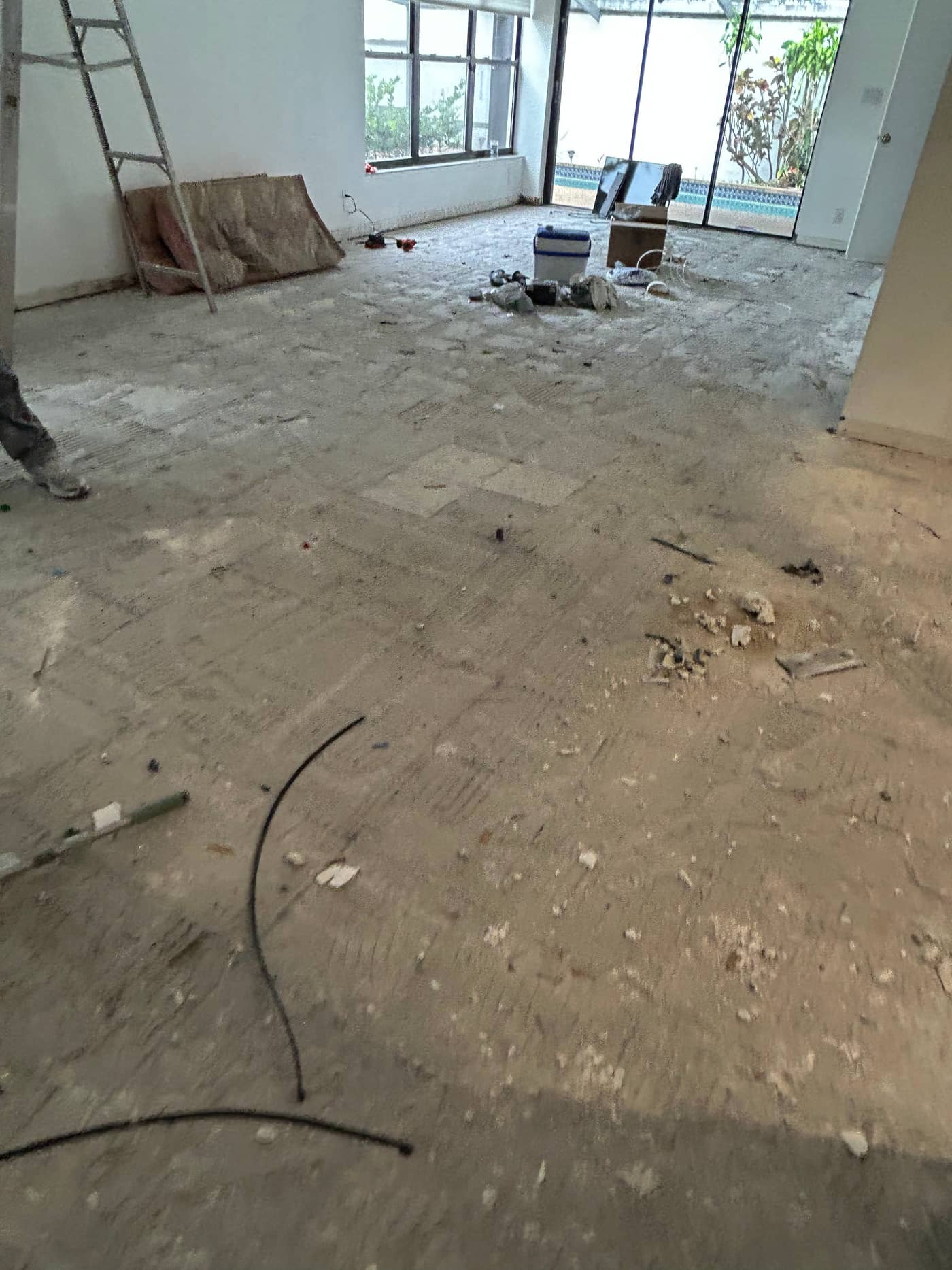 The same room with the debris gone, the floor swept back to the slab and the sliding doors at the far end visible