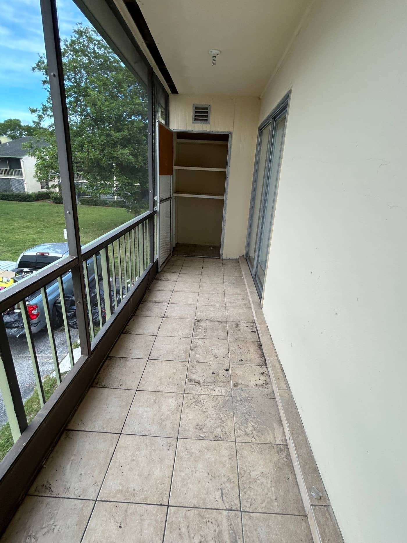 The same screened patio cleared, with the tiled floor open end to end and the yard visible through the screen