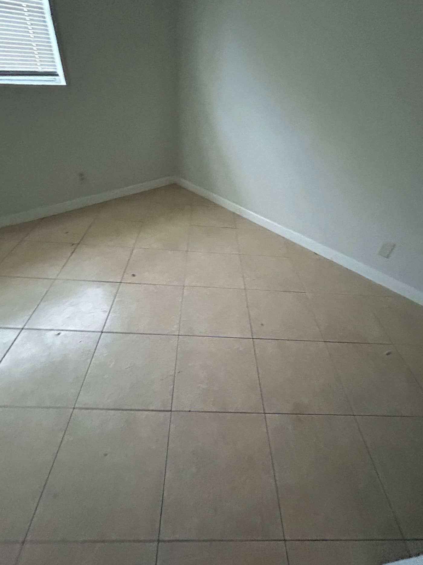 The same corner of the room emptied, showing clean tile and bare walls